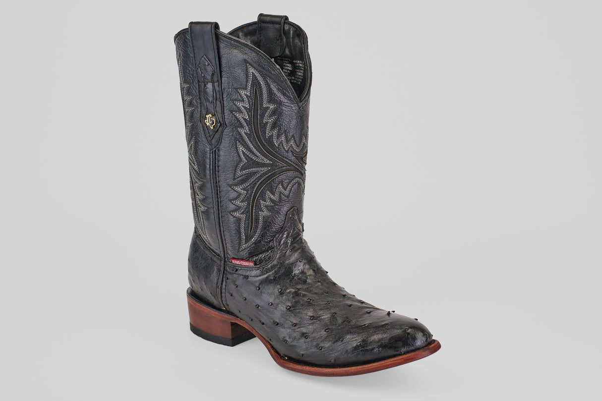 The Exotic Full Quilt Ostrich - Black - Round Toe boot, featuring decorative stitching, a textured ostrich leather foot, brown sole, and low wooden heel, is shown on a plain light gray background.