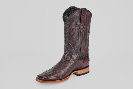 A single Exotic Full Quilt Ostrich boot in Black Cherry with a square toe, featuring intricate shaft stitching and textured ostrich leather, is displayed on a plain gray background.