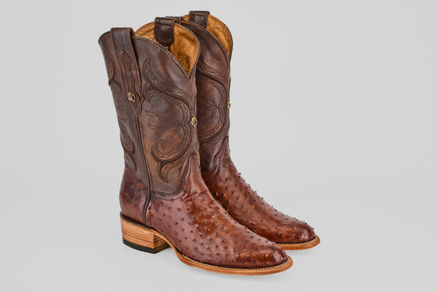 The Austin - Tabaco - Roper Toe men's cowboy boots, made from brown ostrich leather with classic roper toes, detailed stitching, and wooden heels, are displayed side by side on a light gray background.