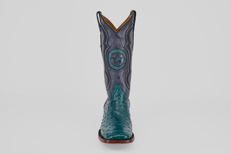 The Austin - Gasoline Green - Square Toe men’s western boot features a teal ostrich leather foot and a dark blue shaft with star and circular stitching, shown from the front on a white background—ideal for ostrich leather boot enthusiasts.