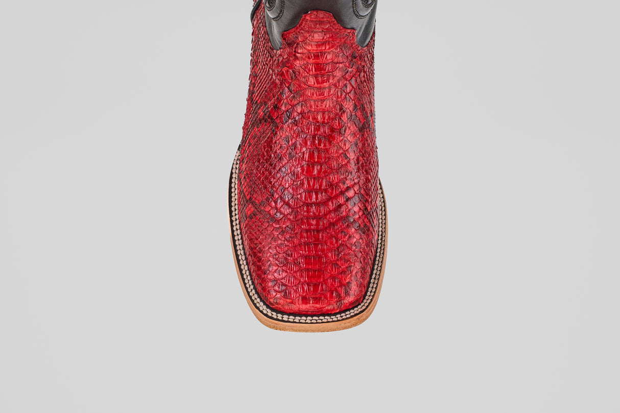 A close-up, top-down view of the Tanner - Ruby - Square Toe cowboy boot highlights its bold red snakeskin, square toe, and decorative stitching along the edge.