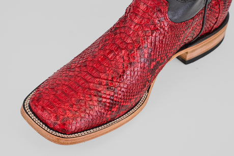 A close-up of the Tanner - Ruby - Square Toe cowboy boot, showcasing its Python Rojo snakeskin, square toe design, and detailed stitching on a light background.