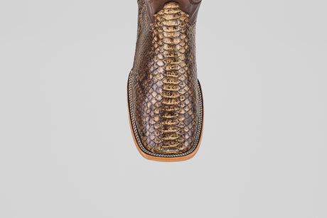 A close-up of the Tanner – Dune – Square Toe boot showcases its shiny python leather finish and detailed stitching on the toe, set against a plain white background—ideal for fans of western-inspired boots.