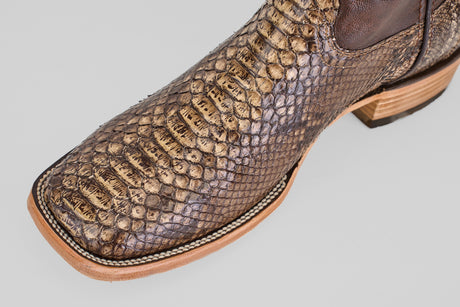 Close-up of the Tanner – Dune – Square Toe boot, crafted from brown python leather with detailed stitching, highlighting its western-inspired design against a light gray background.