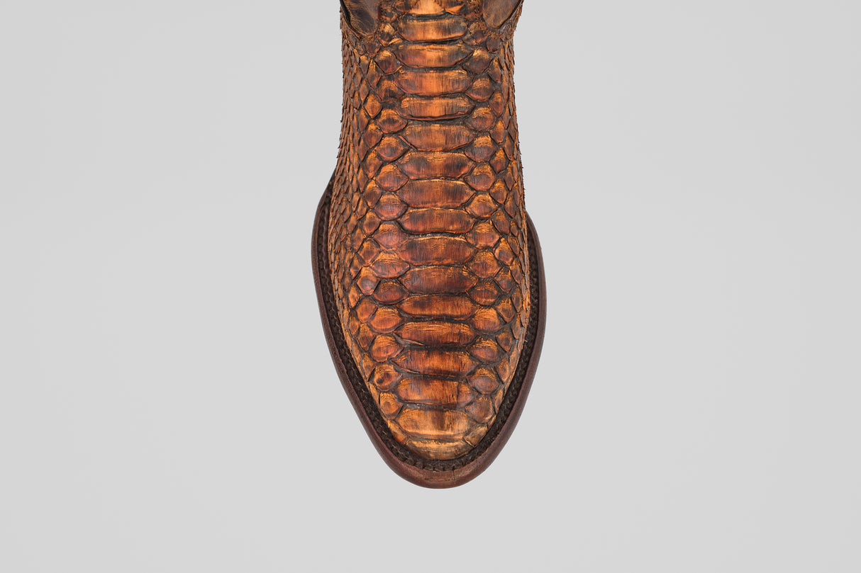 A top-down view of the Tanner – Chestnut – Round Toe boot, showcasing its brown python leather, detailed scale pattern, and dark brown trim around the sole—an ideal choice for western fashion enthusiasts.