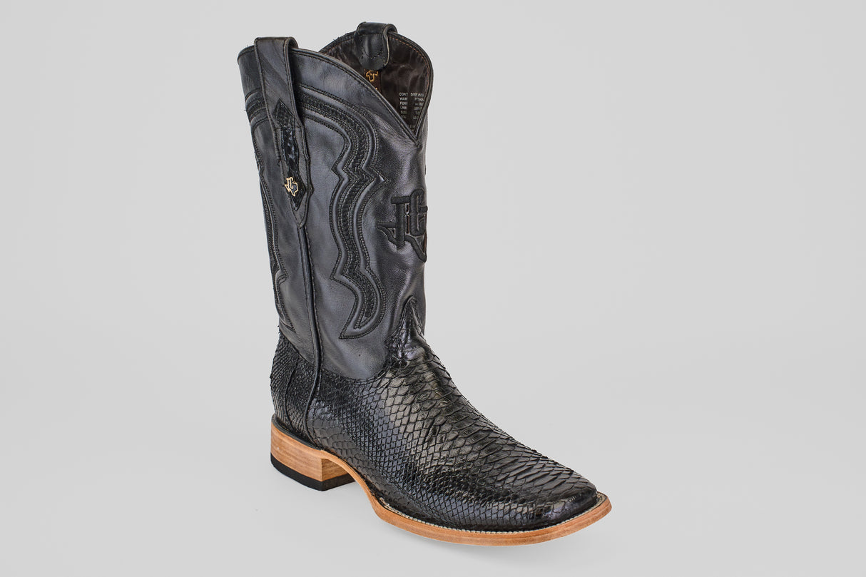 The Tanner - Black - Square Toe cowboy boot features a textured lower section, decorative stitching on the upper shaft, and a light brown wooden heel and sole, all set against a plain white background.