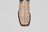 Top view of the Tanner - Natural - Rodeo Toe cowboy boot in tan natural python snakeskin, featuring a square toe, dark brown trim, and wooden sole, set against a plain light gray background.