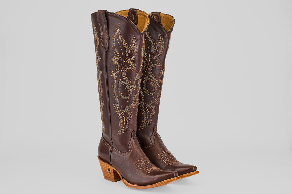 A pair of Allison Dark Moka - Tall Shaft - Snip Toe women's cowboy boots in dark mocha leather with intricate stitching, angled heels, and snip toes stand upright on a light gray background.