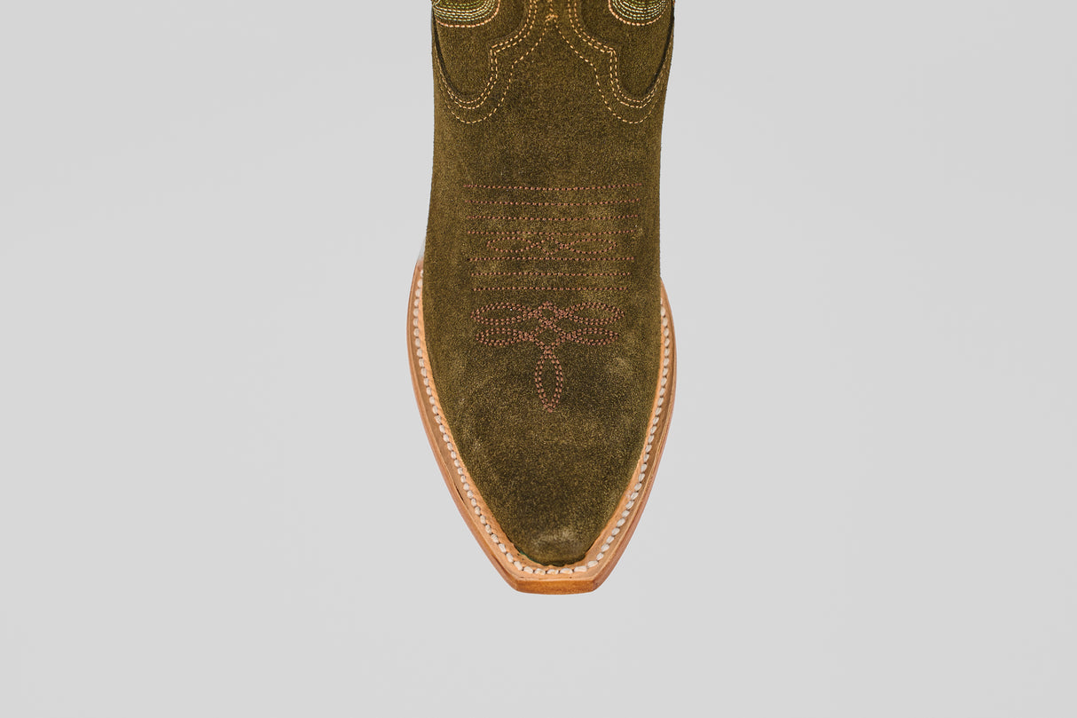 A close-up, top-down view of the Allison Agave - Tall Shaft - Snip Toe women’s boot shows its green suede, pointed toe, decorative stitching, and light brown leather sole against a plain white background.
