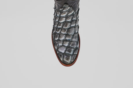 A close-up, top view of the Conor - Newspaper - Roper Toe boot showcases its textured, scale-like pattern and brown sole against a white background—a striking example of exotic leather craftsmanship.