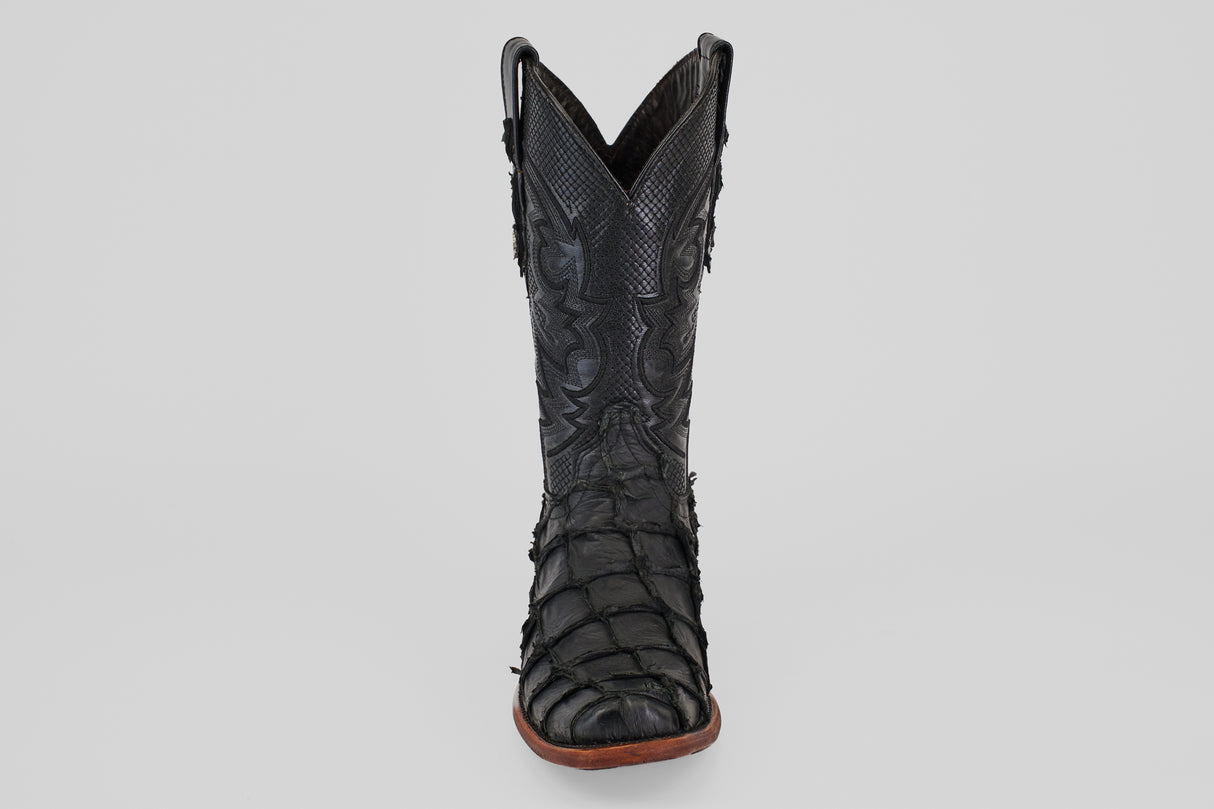 The Conor - Matte Black - Narrow Square Toe cowboy boot features textured, patterned fish leather and a brown sole, displayed upright and facing forward on a plain light gray background.