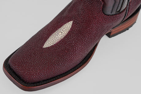 Close-up of the Ranger – Wine – Rodeo Toe cowboy boot, crafted from textured burgundy stingray leather with a white oval inlay on the toe, dark stitching, and a brown wooden heel, set against a light gray background.