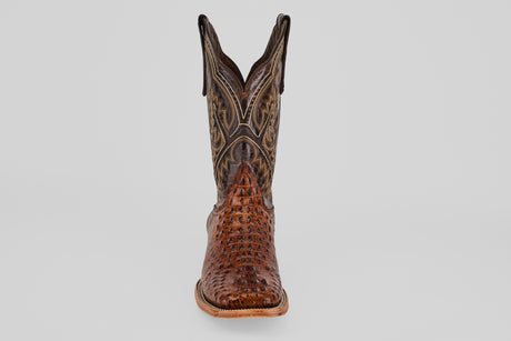 The Hornback Brown - Embossed Leather - Square Toe (E427) boot features a textured, patterned surface and dark stitching, shown front-facing on a light gray background. Ideal for anyone seeking authentic Western style boots.