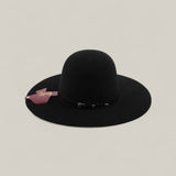 The 10X - Black - TC Hats features a wide brim, rounded crown, elegant decorative band, and a pink tag on the brim, shown against a plain beige background.