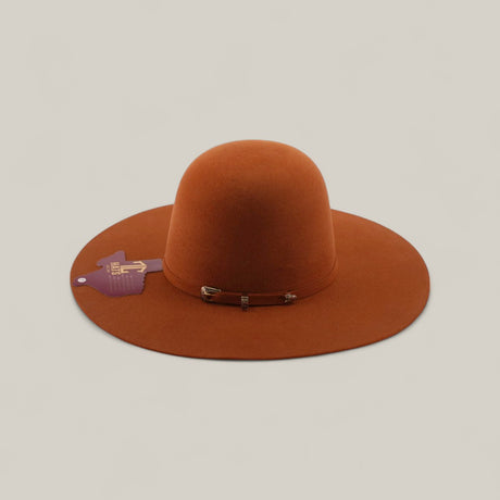 The 4x - Brick - TC Hats features a rust color, open crown, wide brim, rounded crown, decorative metal buckle, purple and gold side tag, and a stylish band, set against a plain beige background.