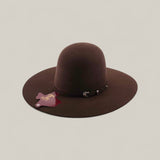 The 4X - Chocolate - TC Hat is a felt Western hat in dark brown, with a wide brim, simple black band, and attached tag, shown against a plain light background.
