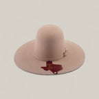 The 4X - Belly - TC Hats is a beige Western hat with a wide brim, shapeable crown, decorative band, and a dark red Texas outline with HALF 3 text and a star on the brim.