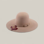 The 4X - Belly - TC Hats is a wide-brimmed, light pink felt Western hat with a thin matching band and gold buckle, maroon tag on the band, and a shapeable crown, shown against a plain light background.