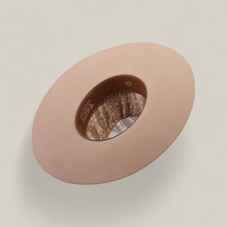 The 4X - Belly - TC Hats is displayed upside down, featuring a beige Western style with a shapeable crown, brown leather inner band, and patterned fabric lining, all set against a plain light background.