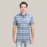 A man wearing the Mens Performance Western Short Sleeve Aztec Print Grey Shirt (PGW10649) faces forward against a plain light background, pairing it stylishly with faded blue jeans and sporting short dark hair.