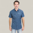 A man stands facing forward against a plain light gray background, wearing the Mens Performance Western Short Sleeve Aztec Print Navy Shirt (PGS10659) and light-washed jeans.