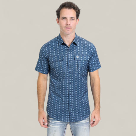 A man stands facing forward against a plain light gray background, wearing the Mens Performance Western Short Sleeve Aztec Print Navy Shirt (PGS10659) and light-washed jeans.