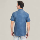 A man faces away from the camera in a Mens Performance Western Short Sleeve Aztec Print Navy Shirt (PGS10659) and light blue jeans with decorative back pocket stitching, standing against a plain background.