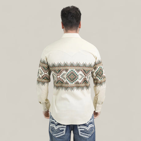 A man faces away, wearing the Mens Western Modern Fit Cotton/Spandex Long Sleeve Beige Shirt with snaps (WPL10677) featuring green, brown, and beige geometric patterns on the back and arms, paired with blue jeans with white-stitched pockets.