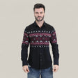 A man wears the Mens Western Modern Fit Cotton/Spandex Long Sleeve Black Shirt with Snaps (WPL10750), featuring red and white geometric patterns, paired with blue jeans, standing against a plain light grey background.