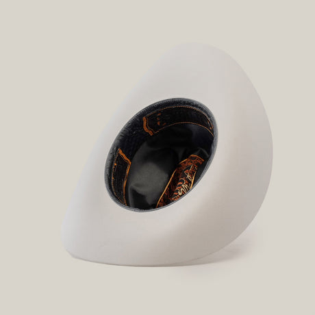 A 1000X Imperial White hat rests on its side against a plain background, revealing the dark brown and orange patterned interior with black lining, offering a glimpse of 100% genuine mink craftsmanship.