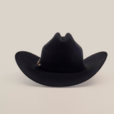 The 10X Jerarca Black is a handcrafted black cowboy hat made from fur felt, with a wide brim and distinctive top crease. It features a small decorative band on one side, exemplifying classic western headwear against a plain white background.