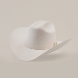 The 6X Real White hat is a luxury piece of Western headwear, featuring a wide brim and decorative band. Handcrafted from fur felt by skilled artisans, it is slightly tilted to accentuate its classic western style against a plain background.