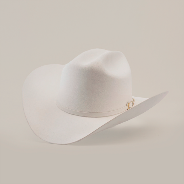 The 6X Real White hat is a luxury piece of Western headwear, featuring a wide brim and decorative band. Handcrafted from fur felt by skilled artisans, it is slightly tilted to accentuate its classic western style against a plain background.