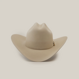 The 1000X Imperial Belly by Larry Mahan is a beige western hat with a wide brim and slightly creased crown, highlighted by a small decorative charm on the band, displayed against a plain white background