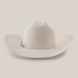 The 10X Jerarca White is a white cowboy hat made from premium fur felt, featuring a wide brim and distinctive crown crease. Adorned with a small decorative band, this classic western headwear embodies timeless style against a minimalist backdrop, highlighting its refined design.