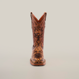 The Handtooled Leave Orix cowboy boot exhibits a front view of premium brown cowhide leather, adorned with floral and geometric embroidery on white. Its elegant design is complemented by handtooled details and a slip-resistant sole for enhanced stability.