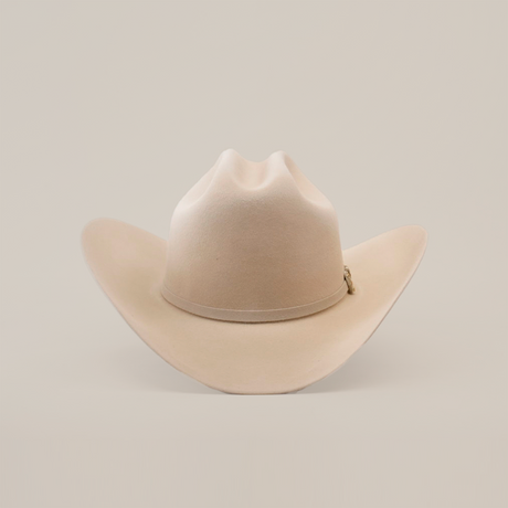 The 10X Jerarca Belly is a beige fur felt cowboy hat with a wide brim and creased crown, embodying classic western style, set against a plain white background.