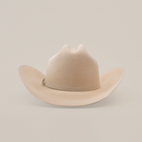 The 10X Jerarca Belly is a beige cowboy hat with a curved brim and distinct top crease, made from fur felt. Featuring a subtle hatband, this piece of Western headwear is displayed against a plain white background.