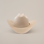 The 100X Independencia Belly, a beige cowboy hat made of premium full beaver fur, features a wide brim and a stylish crown crease, elegantly displayed on a plain white background.