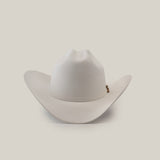 The 1000X Imperial White hat features a wide brim and slightly curved crown against a plain white background. Adorned with a small decorative emblem, this 100% genuine mink accessory exudes charm, sophistication, and style.