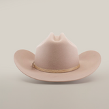 The 6X Country Belly, a beige cowboy hat made from premium sheep wool, features a wide brim and crown crease on a white backdrop. A light brown braided band adds rustic charm to this classic felt hat.