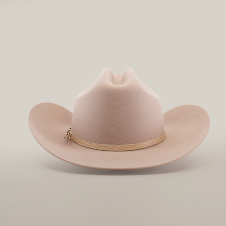 The 6X Country Belly, a beige cowboy hat made from premium sheep wool, features a wide brim and crown crease on a white backdrop. A light brown braided band adds rustic charm to this classic felt hat.