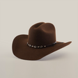 The 6X Dallas Brown felt hat embodies Western elegance, featuring a brown hue, curved brim, and a black band with silver conchos. Made from quality sheep wool and set against a plain white background, it captures frontier spirit.